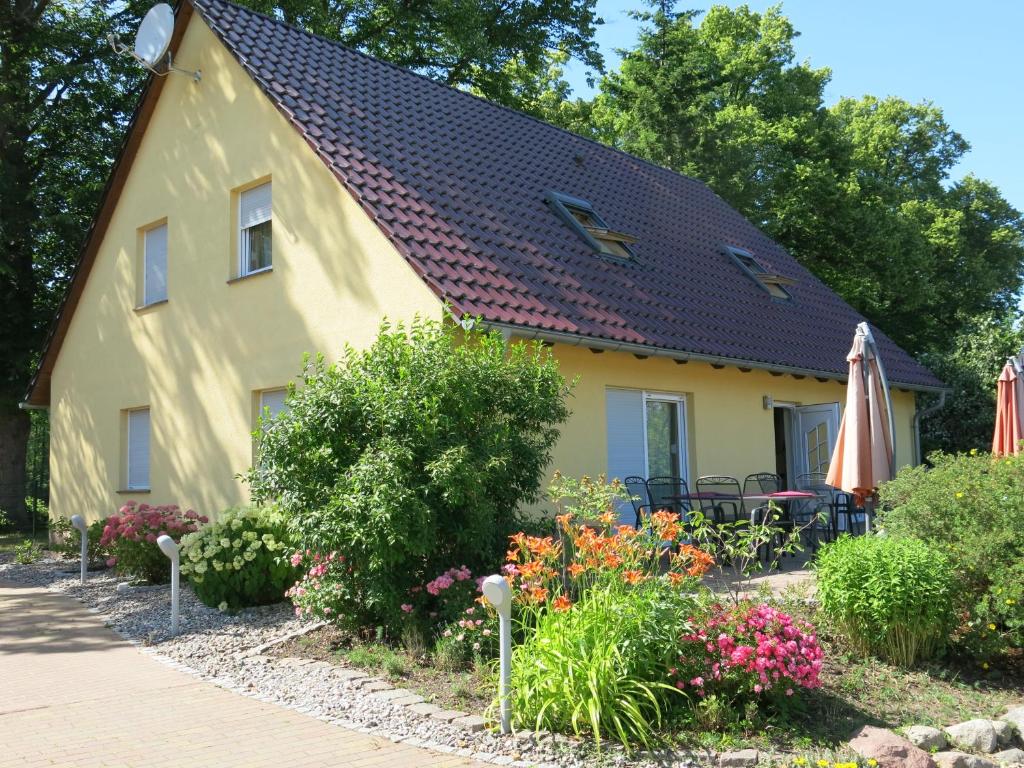 una casa amarilla con sombrilla y algunas flores en Schölzke‘s Ferienhaus en Ralswiek