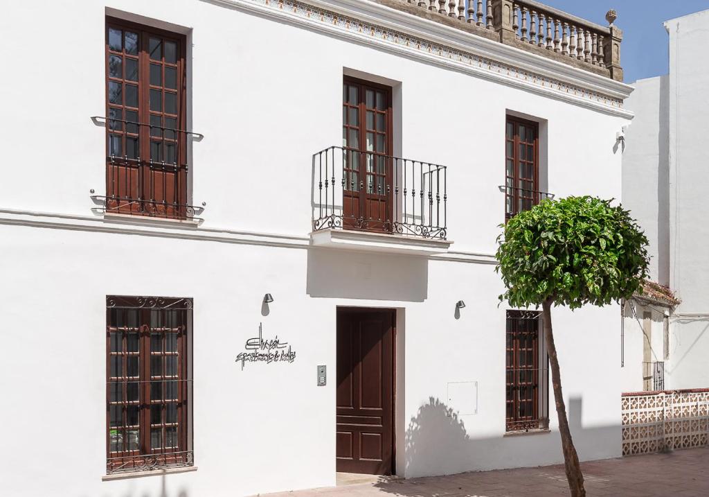 un edificio bianco con finestre, una porta e un albero di Chacón Apartments & Suites a Estepona