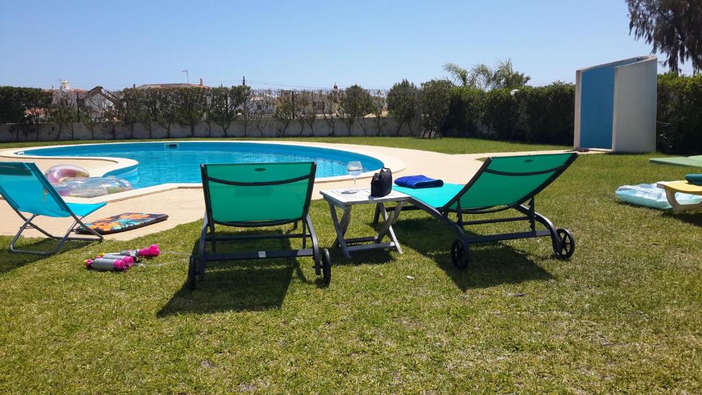 2 sillas y una mesa junto a la piscina en Villas Sol e Poesia, en Albufeira