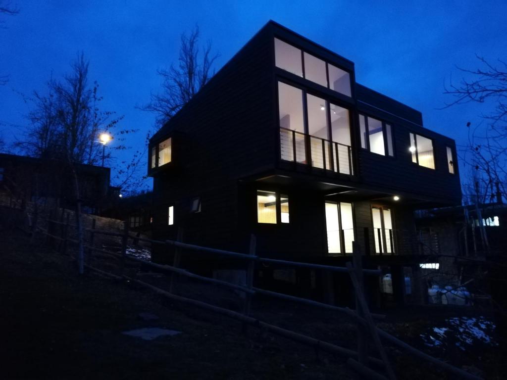 une maison noire la nuit avec les lumières allumées dans l'établissement Refugio Kondortal, à Farellones