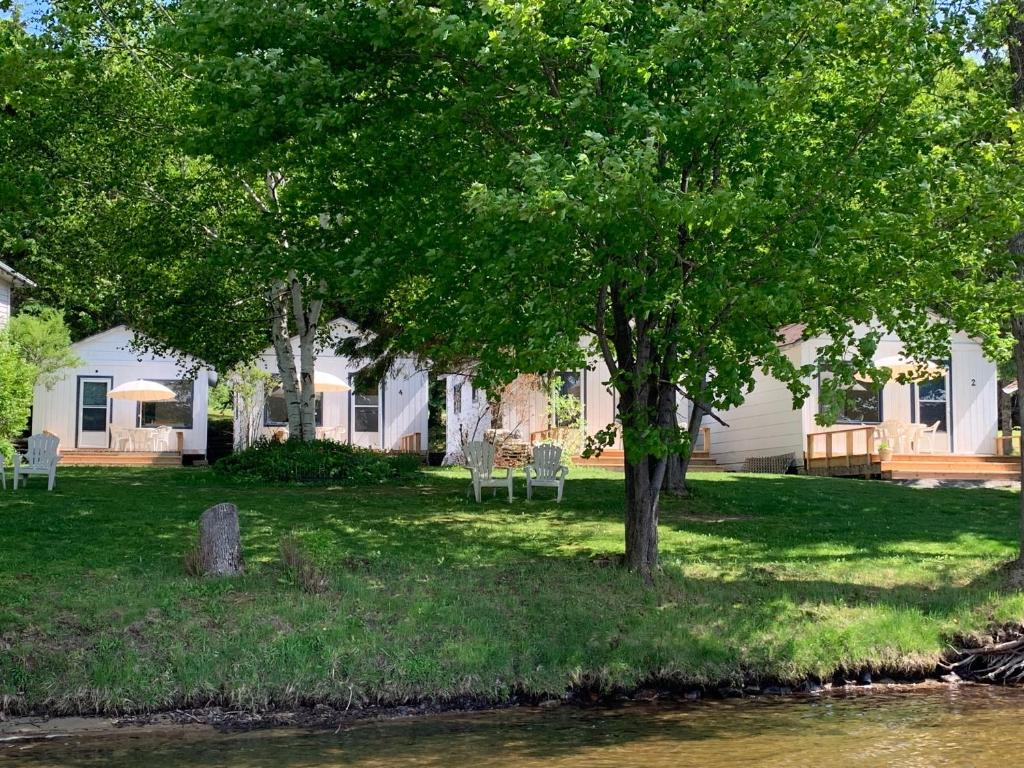 a house with chairs and a tree next to a river at Beachside on Lake Muskoka in Port Carling