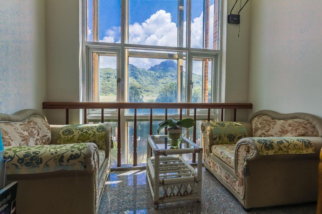 a living room with two couches and a large window at Kenting Maya-House B&amp;B in Kenting