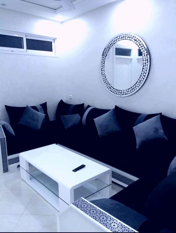 a living room with a black couch and a mirror at Rif Appartment in Al Hoceïma