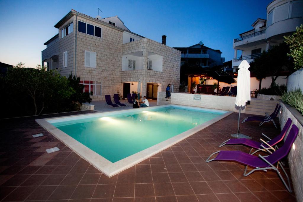 a swimming pool with purple chairs next to a house at Villa Marijeta Hvar in Hvar