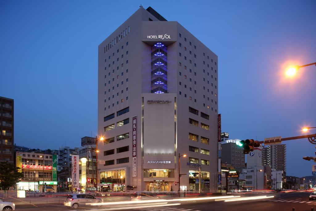 een hoog gebouw met een nissan bord erop bij Hotel Resol Sasebo in Sasebo