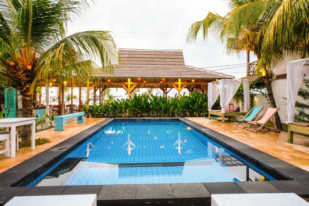 uma piscina em frente a uma casa com palmeiras em Sedjiwa em Gili Air