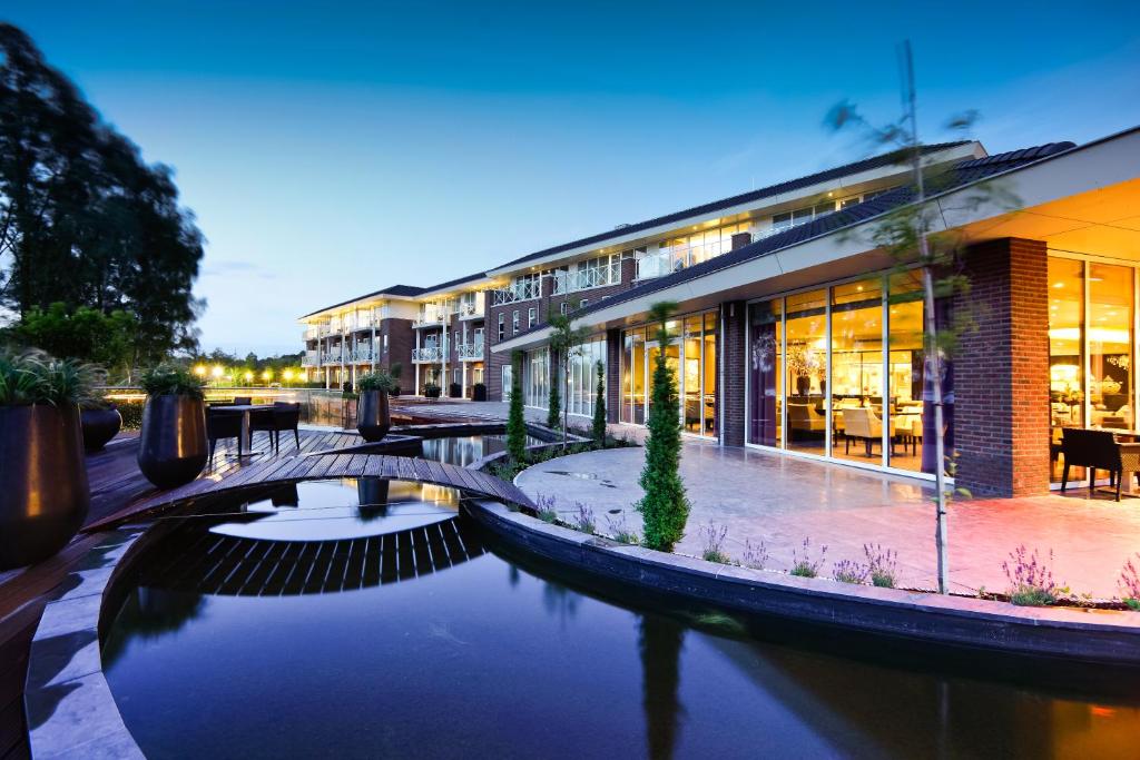 a bridge over a river in front of buildings at Hotel Thermen Bussloo - Apeldoorn in Bussloo