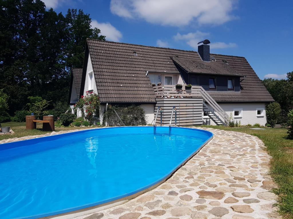 a house with a blue swimming pool in front of a house at Landhaus-Lässig in Soltau