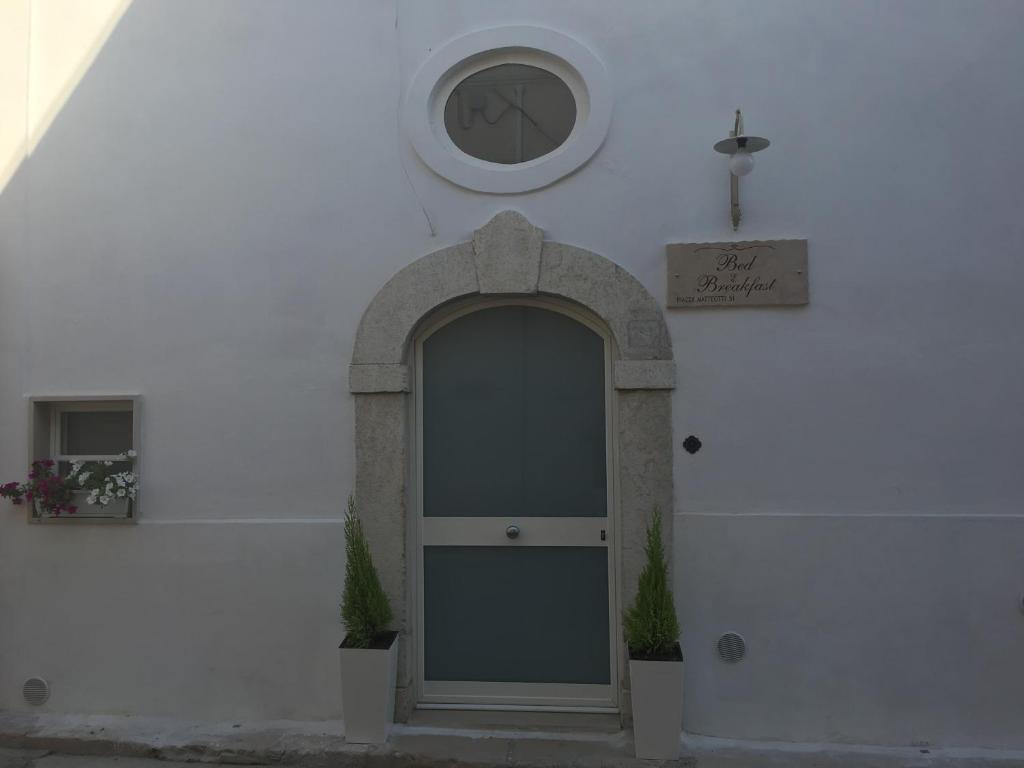 un edificio bianco con una porta e un orologio sul muro di Bed & Breakfast Piazza Matteotti a Stornara