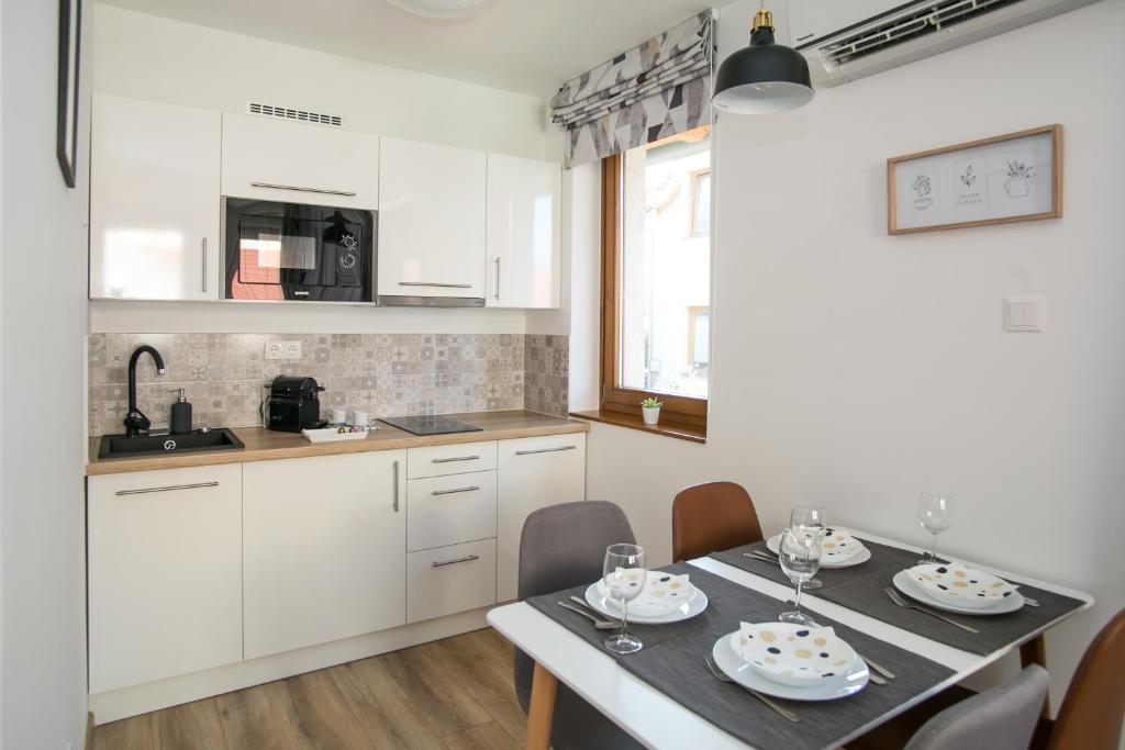 a kitchen with white cabinets and a table with chairs at Ormani Modern Stúdióapartman in Pécs