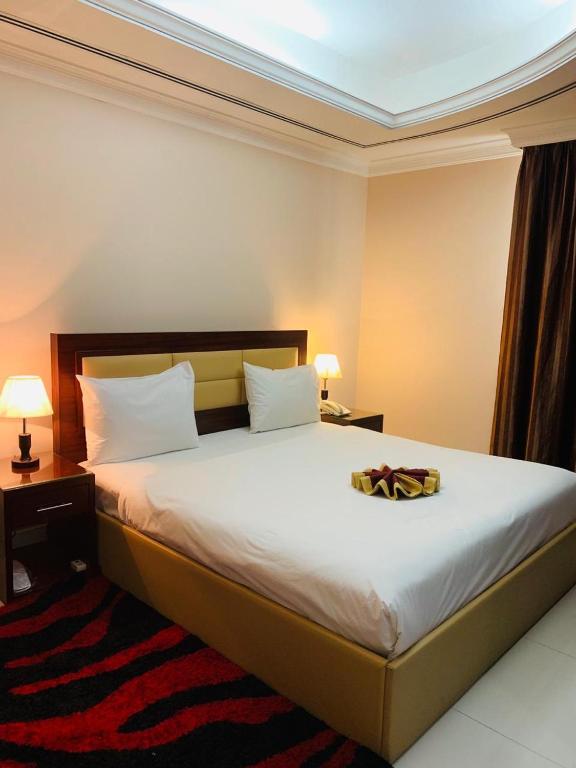 a bedroom with a large bed with white sheets at Hala Inn Hotel Apartments - BAITHANS in Ajman 