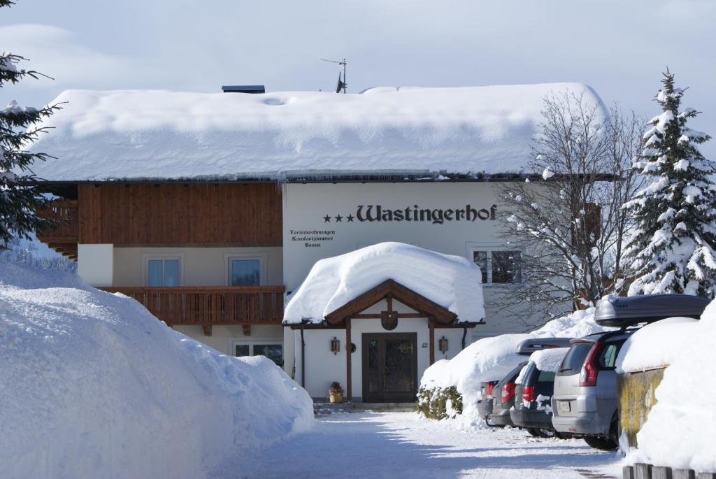 a building covered in snow with cars parked in front at Wastingerhof in Obertilliach