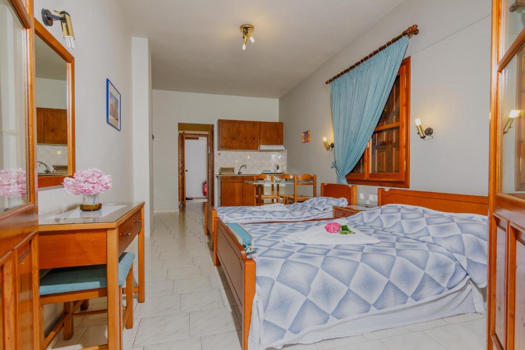 a bedroom with a bed and a desk and a kitchen at Charoula in Platanias