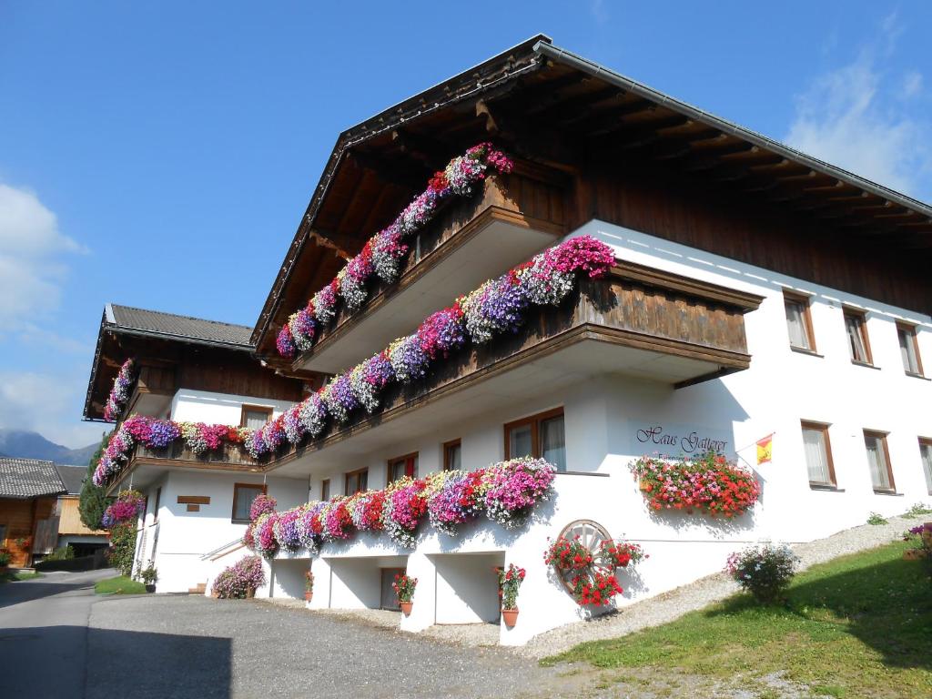 Ein weißes Gebäude mit vielen Blumen drauf. in der Unterkunft Appartement Haus Gatterer in Obertilliach
