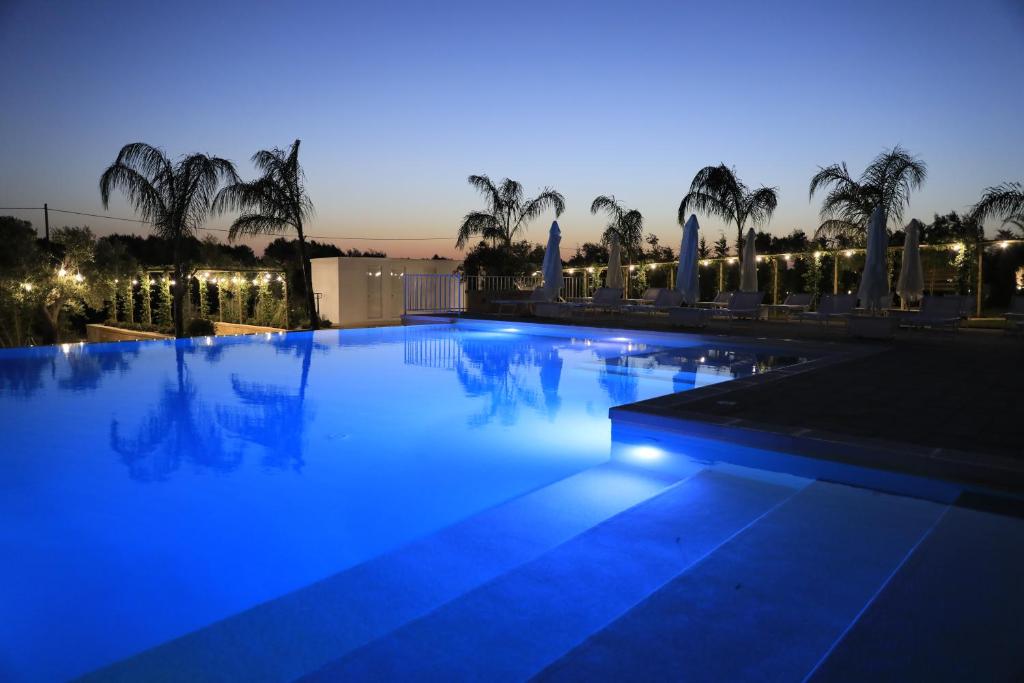 una piscina por la noche con palmeras y luces en L'Ulivo e la Stella, en Porto Cesareo