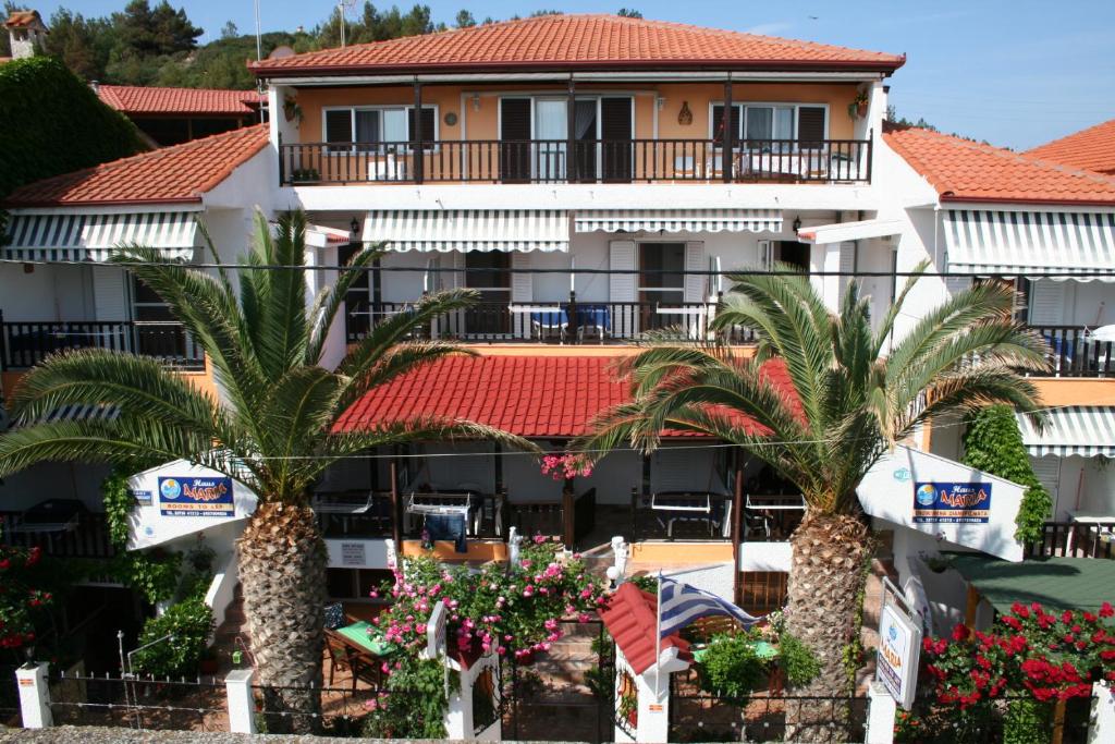 a hotel with palm trees in front of a building at Haus Maria in Nea Potidaea