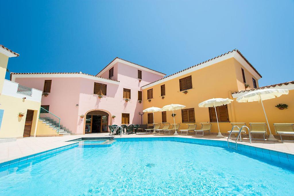 einem Pool vor einem Gebäude mit Stühlen und Sonnenschirmen in der Unterkunft Residence Cala Viola in Cala Liberotto