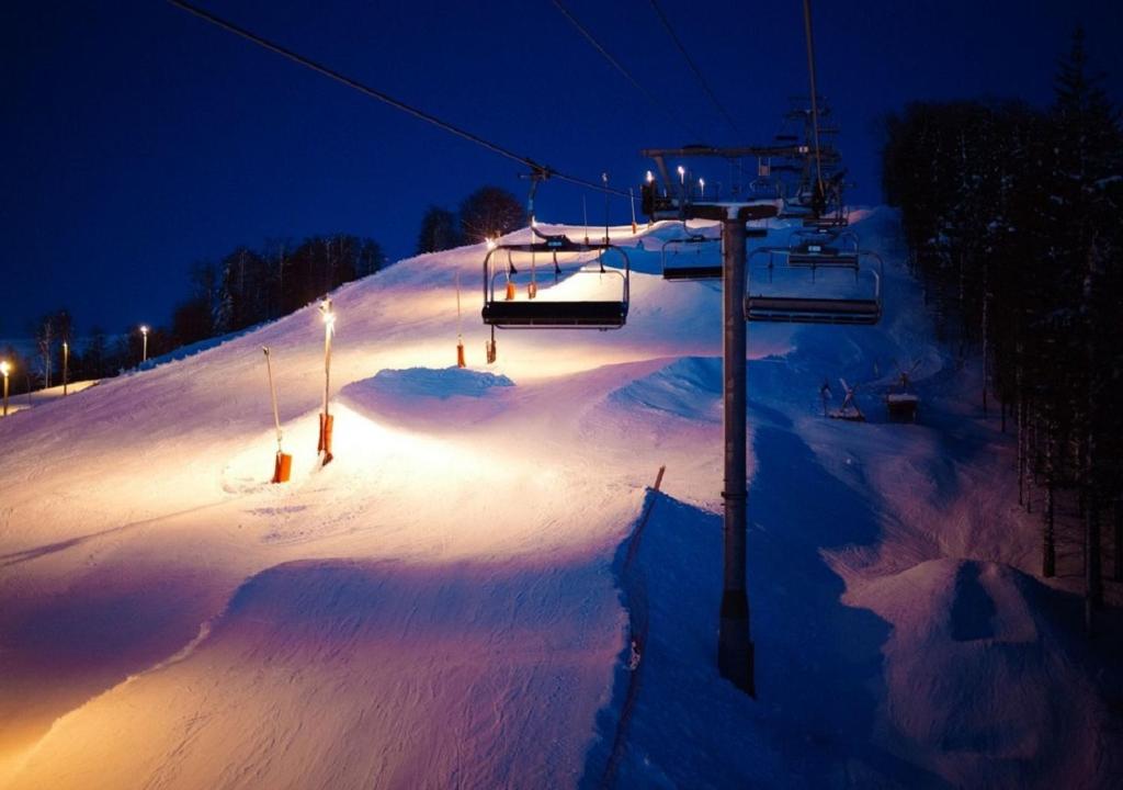 a snow covered slope with a ski lift at night at L'ourson rider in La Bresse