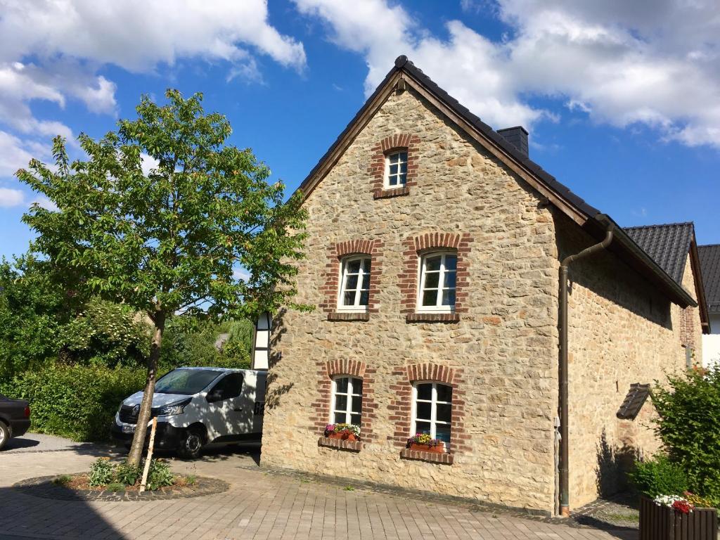 ein Steingebäude mit drei Fenstern und einem Baum in der Unterkunft Freistaat Eifel in Nettersheim