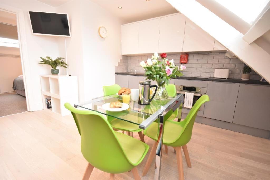 a kitchen with a glass table and green chairs at Apt 3, Opera House ensuite 4th Floor by Indigo Flats in London