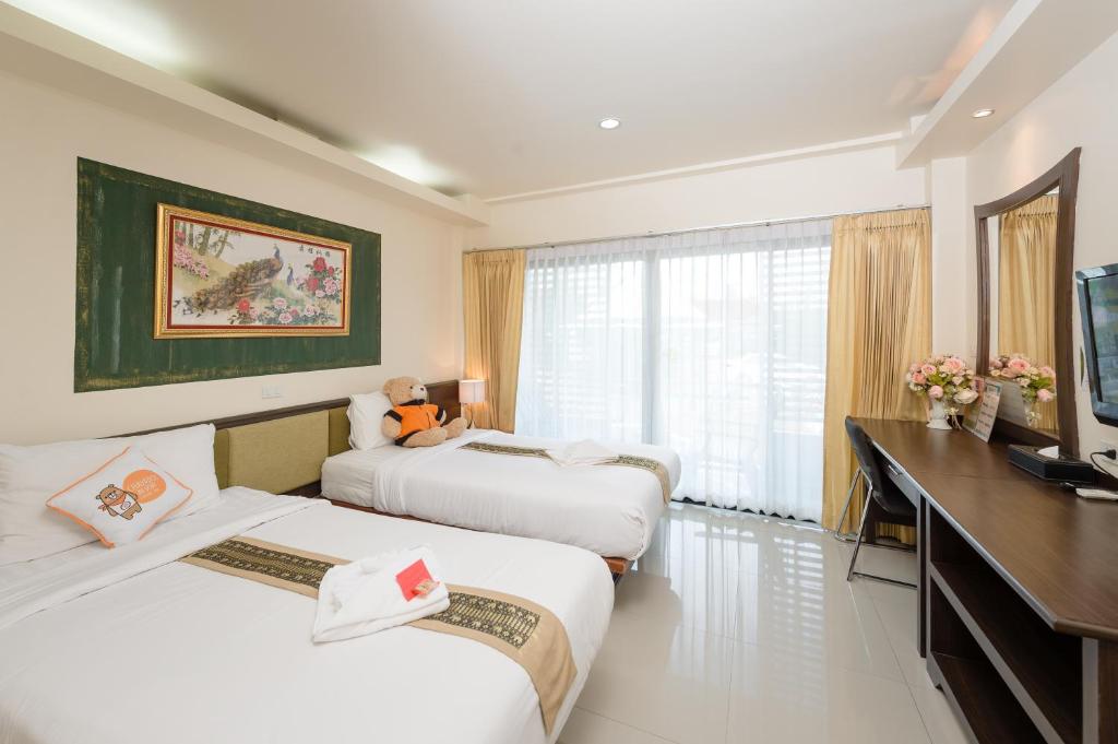 a hotel room with two beds and a desk at Chayadol Resort - SHA Extra Plus in Chiang Rai