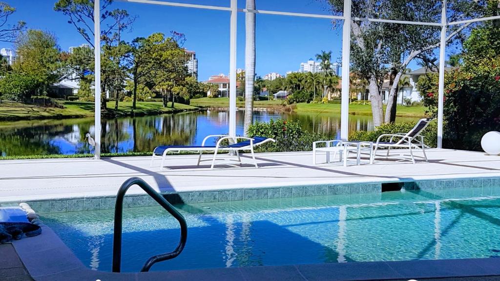 a swimming pool with two chairs next to a lake at Exclusive Villa - Lakeside, 4 Minutes to Private Beach in Naples