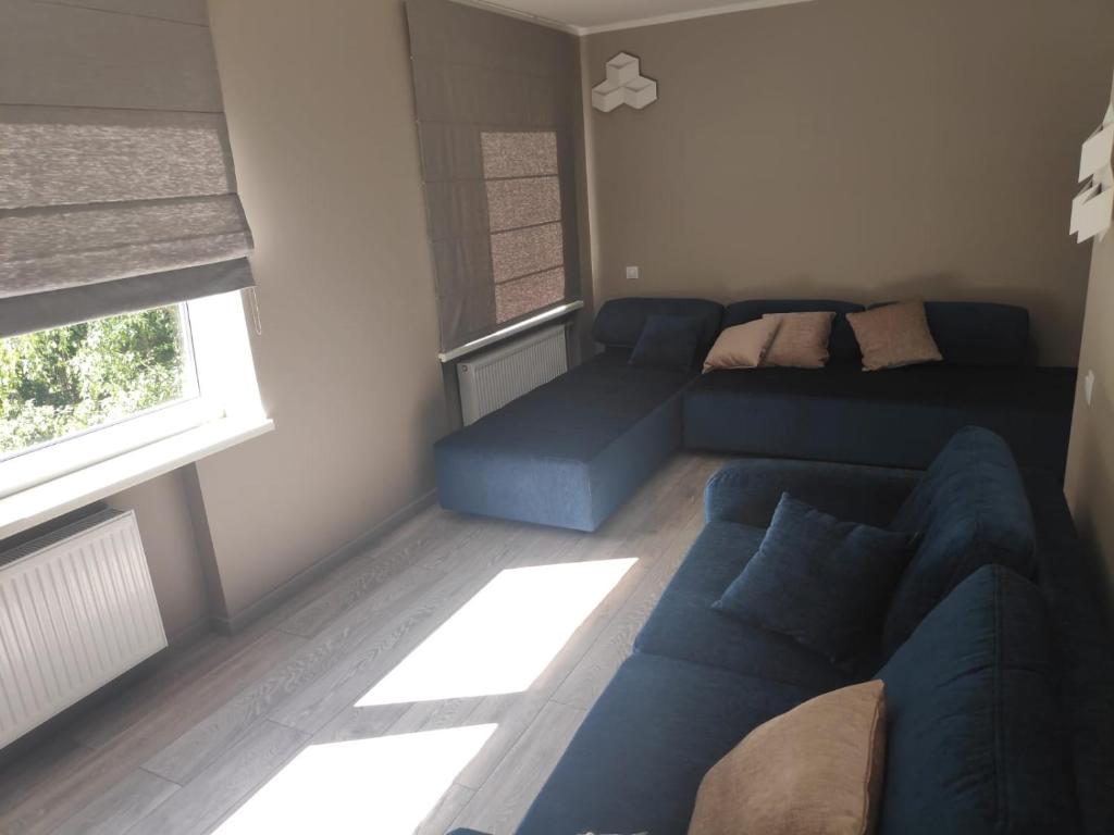 ein Wohnzimmer mit einem blauen Sofa und einem Fenster in der Unterkunft MD Apartments in Jūrmala