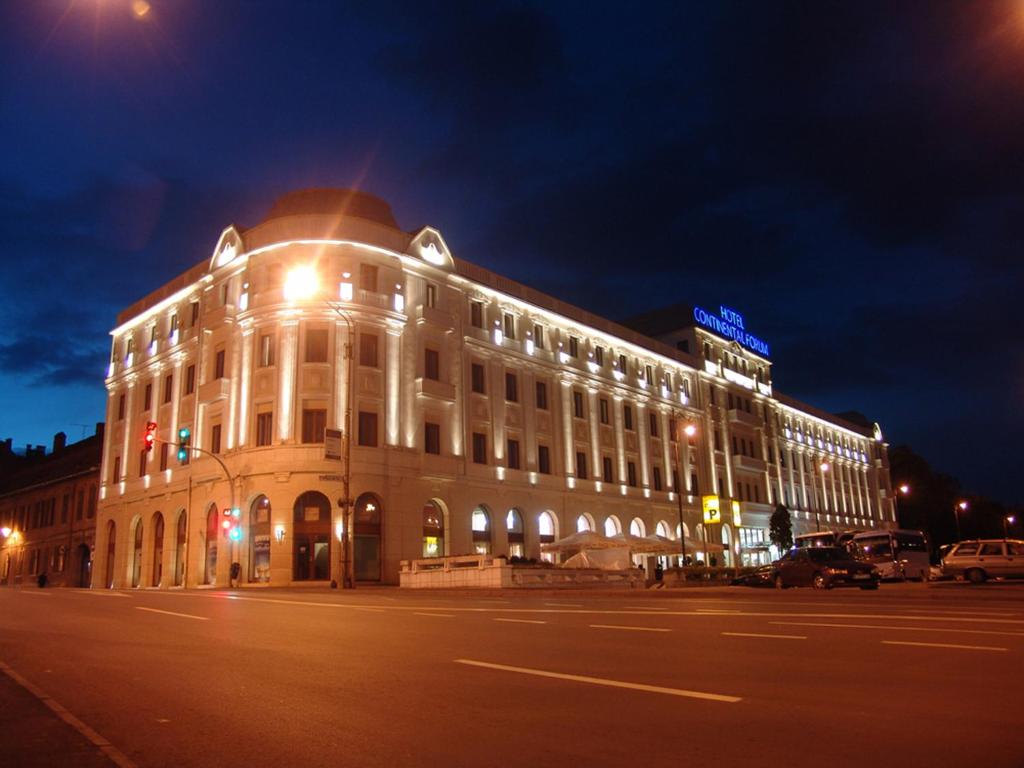 un edificio iluminado en una calle por la noche en Continental Forum Sibiu, en Sibiu
