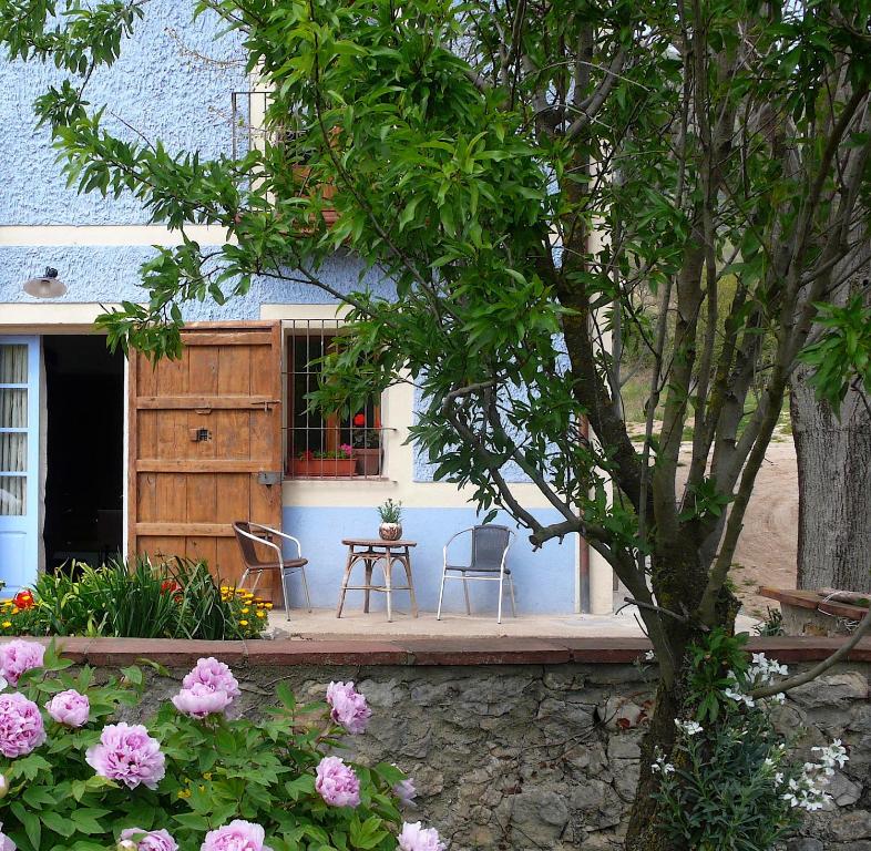 una casa con 2 sillas, una mesa y flores en La Casanova de Beuda, en Beuda