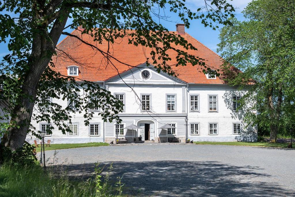 ein großes weißes Haus mit orangefarbenem Dach in der Unterkunft Västanå Slott in Gränna