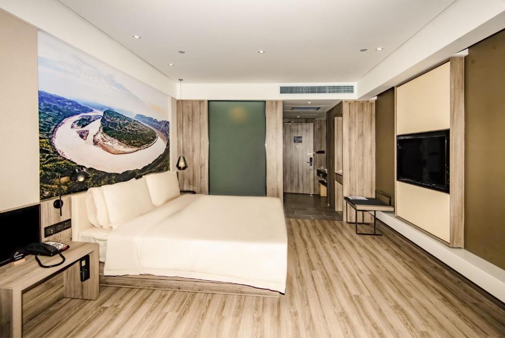 a bedroom with a large white bed and a flat screen tv at Atour Hotel Yuyang West Road in Yulin
