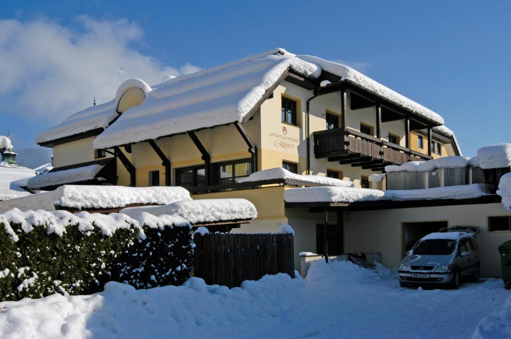 una casa cubierta de nieve con un coche aparcado delante de ella en Café Rainer, en Sankt Johann in Tirol