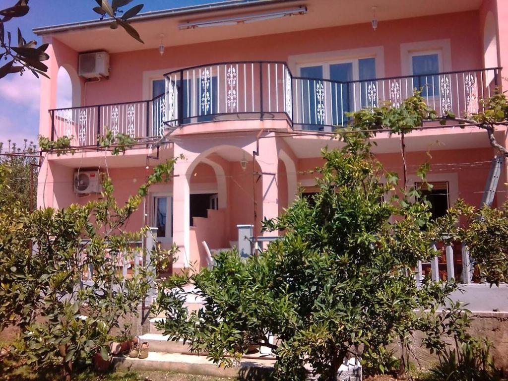 uma casa cor-de-rosa com uma varanda por cima em Apartman Laura em Kaštela