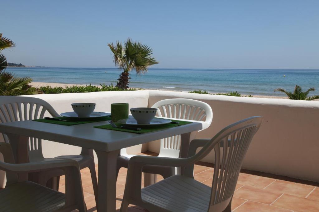 a table and chairs on a balcony with the beach at Apartamentos LLorca in Platja de l’Almadrava