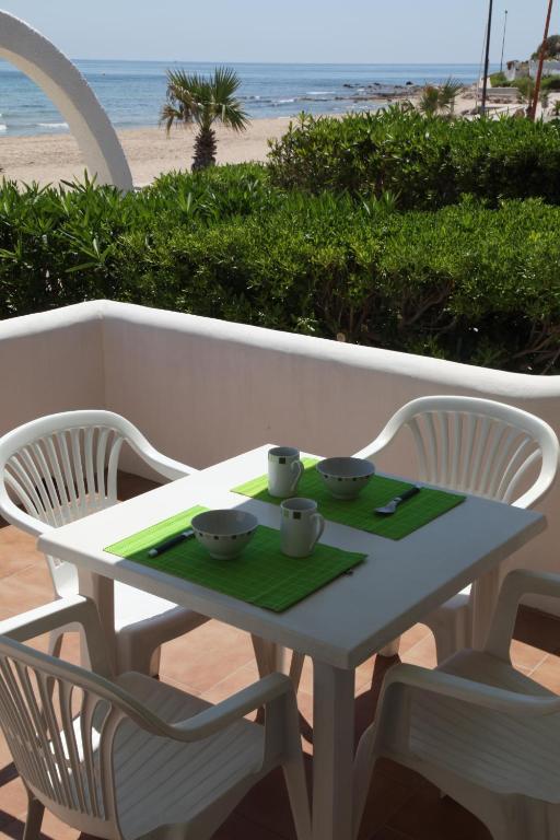 a white table with three bowls on it with a beach at Apartamentos LLorca in Platja de l’Almadrava