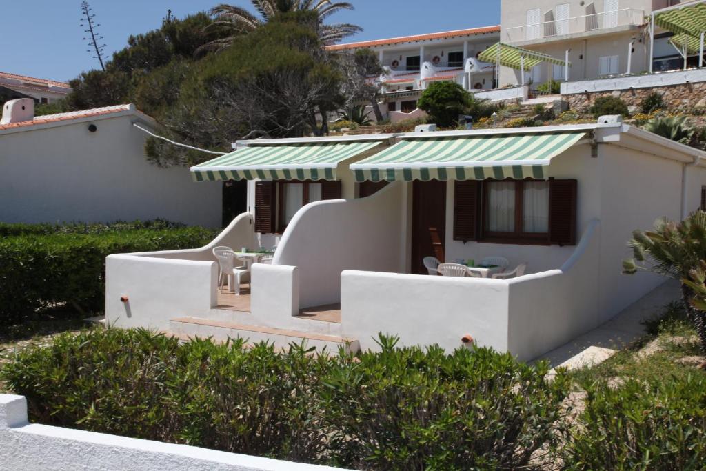 a white house with a green awning at Apartamentos LLorca in Platja de l’Almadrava