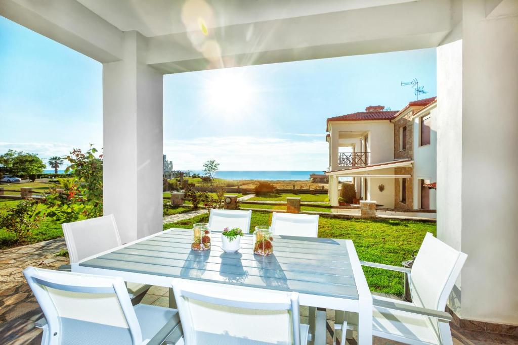 einen Tisch und Stühle auf einer Terrasse mit Meerblick in der Unterkunft Sunset Villas in Posidi