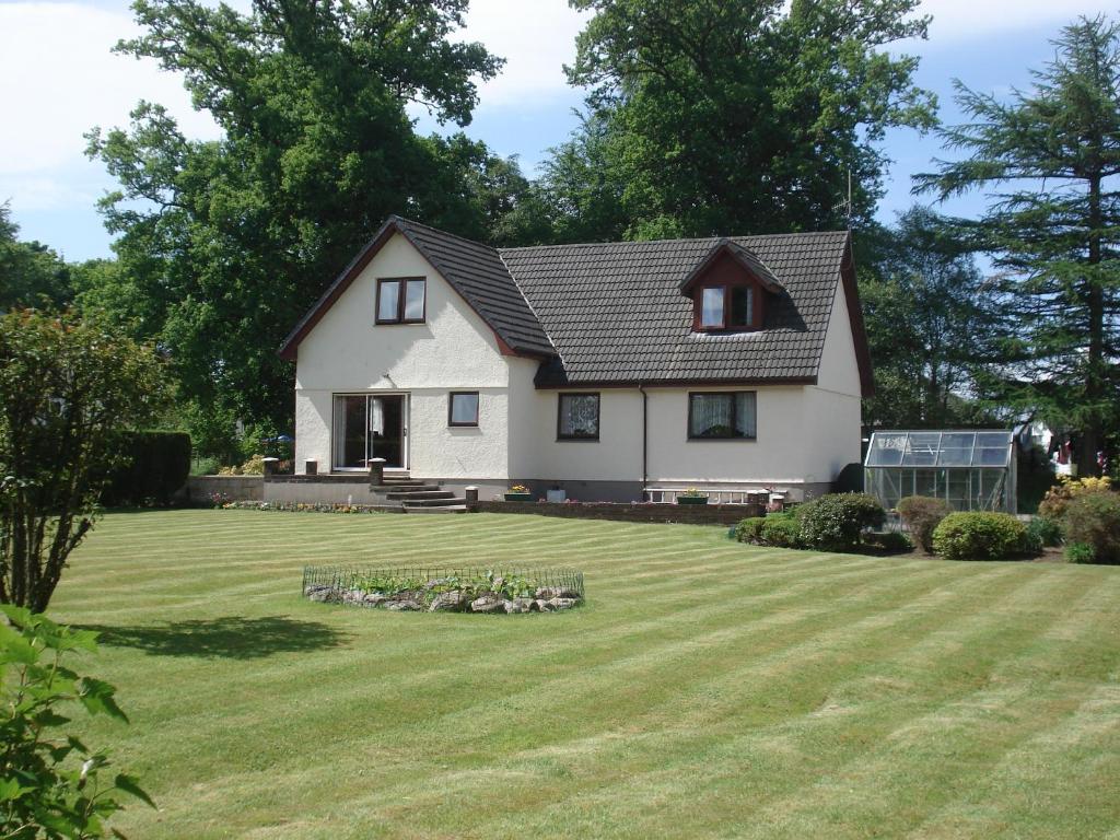 a white house with a large yard at Thistle Cottage in Fort William