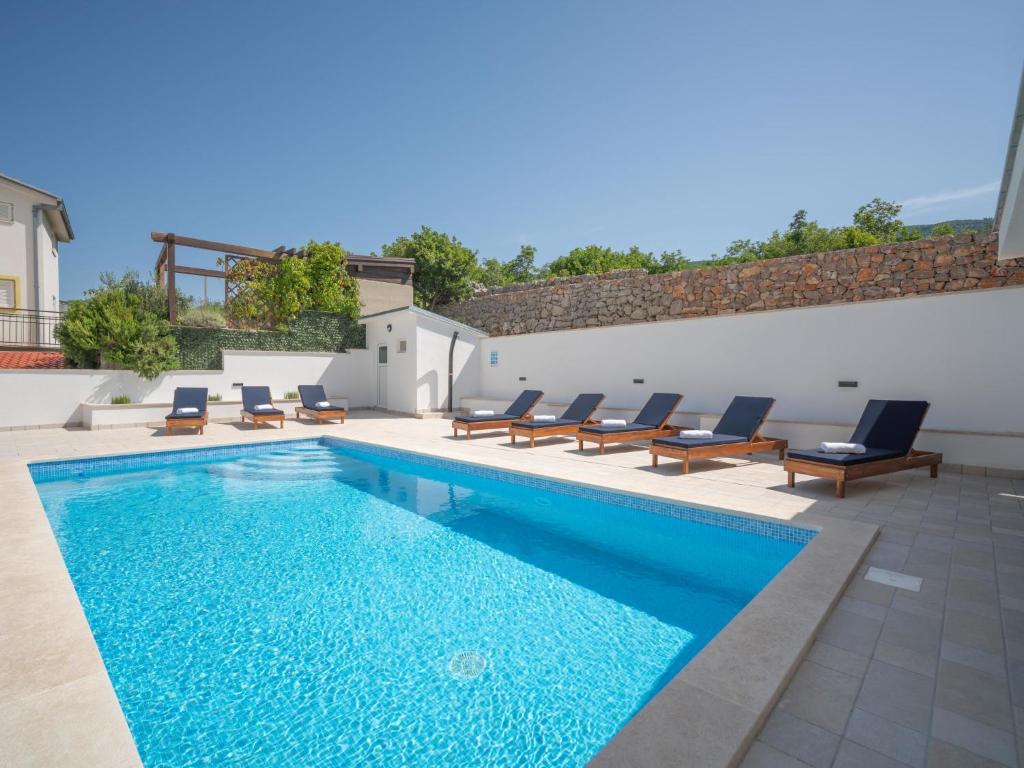 a swimming pool with lounge chairs next to a building at Apartment Josipa-2 by Interhome in Klenovica