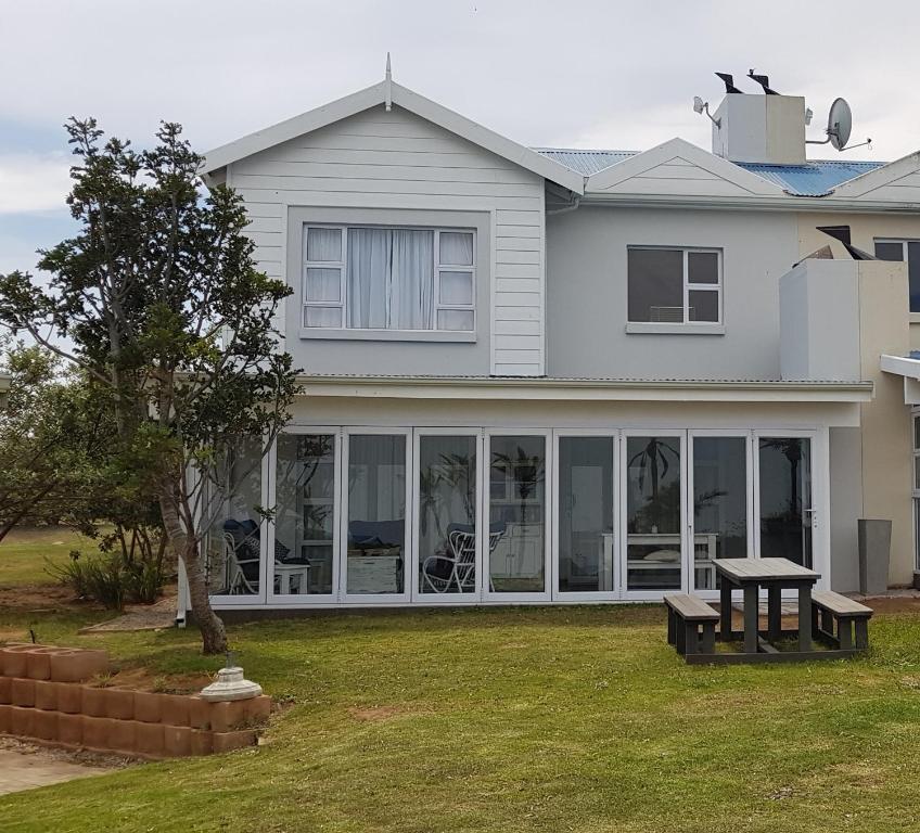 a house with large windows and a bench in the yard at Lodge 90 - Pinnacle Point Estate in Mossel Bay