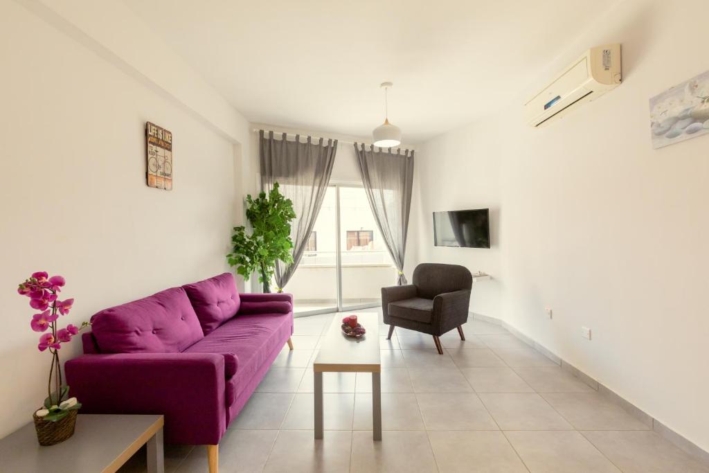- un salon avec un canapé violet et une chaise dans l'établissement Savvas City Centre Flat, à Larnaka