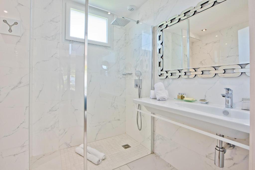 a white bathroom with a shower and a sink at Hôtel La Villa Cap d’Antibes in Juan-les-Pins