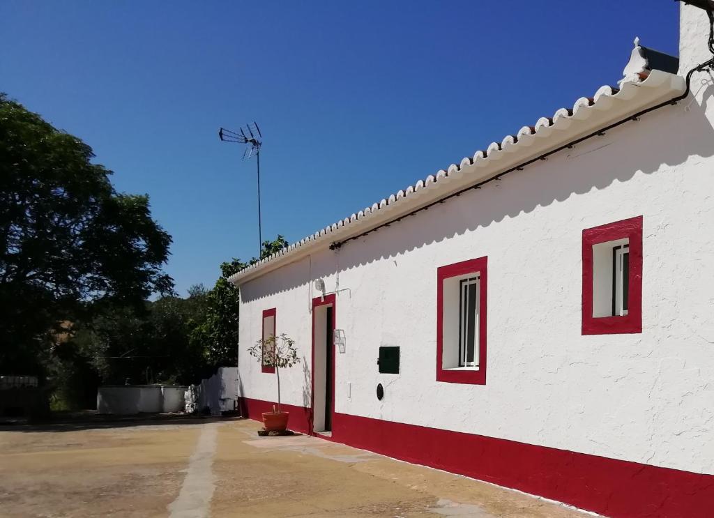 um edifício branco com janelas vermelhas e uma porta vermelha em Monte da Cruz 18 em Évora Monte