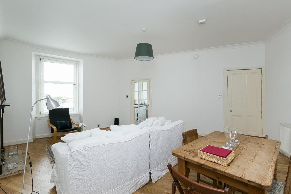 salon z białą kanapą i stołem w obiekcie St Margaret's Loch Apartment w Edynburgu