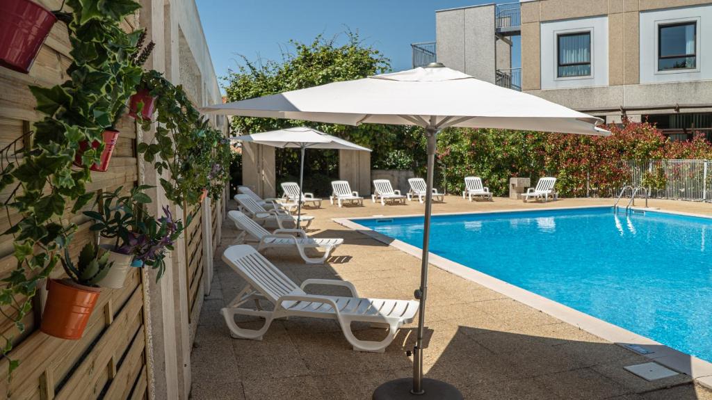ein Pool mit Liegestühlen und einem Sonnenschirm neben einem Pool in der Unterkunft Mercure Niort Marais Poitevin in Niort