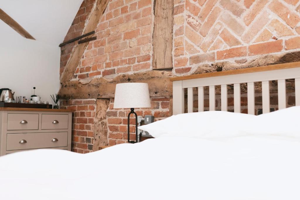a bedroom with two beds and a brick wall at Tuppenhurst Barn in Rugeley