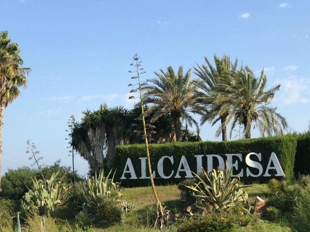 un panneau devant une haie plantée de palmiers dans l'établissement Penthouse Charming Nueva Alcaidesa, à Alcaidesa