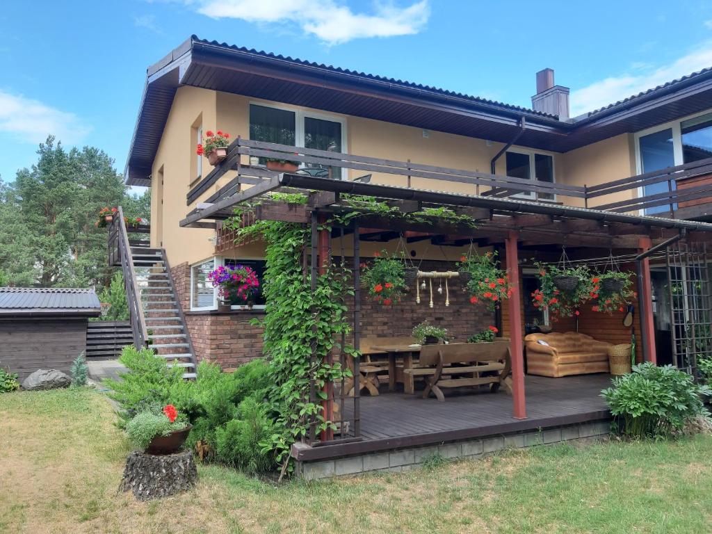 a house with a deck with a bench and flowers at Apartamentai pas Danutę in Prienai
