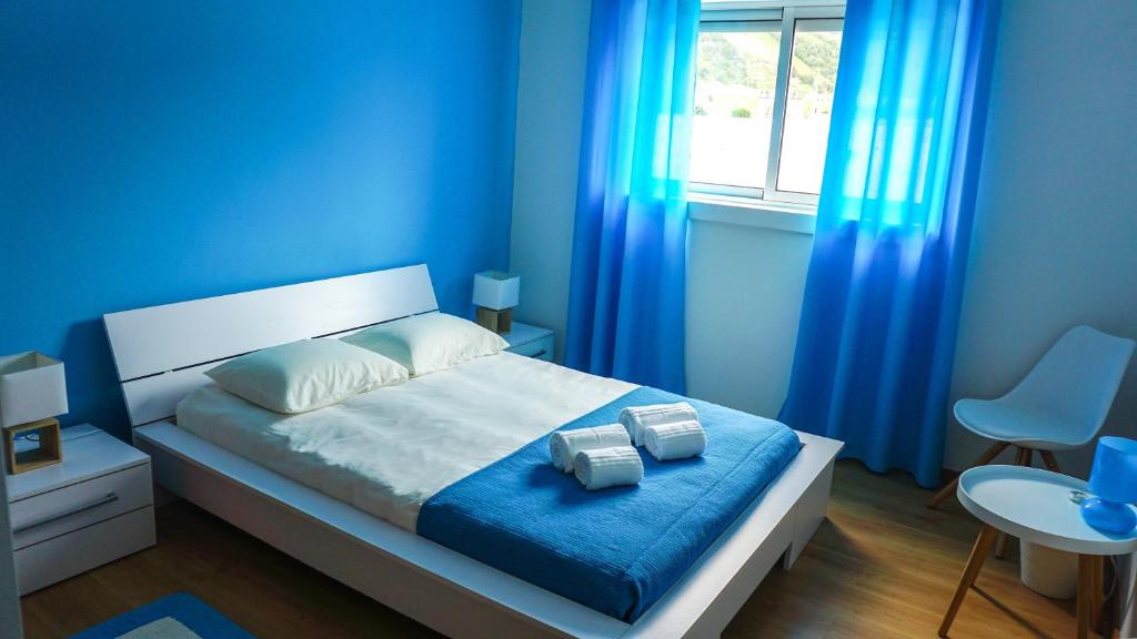 1 dormitorio azul con 1 cama con cortinas azules en Vila Relvão, en Vila Franca do Campo