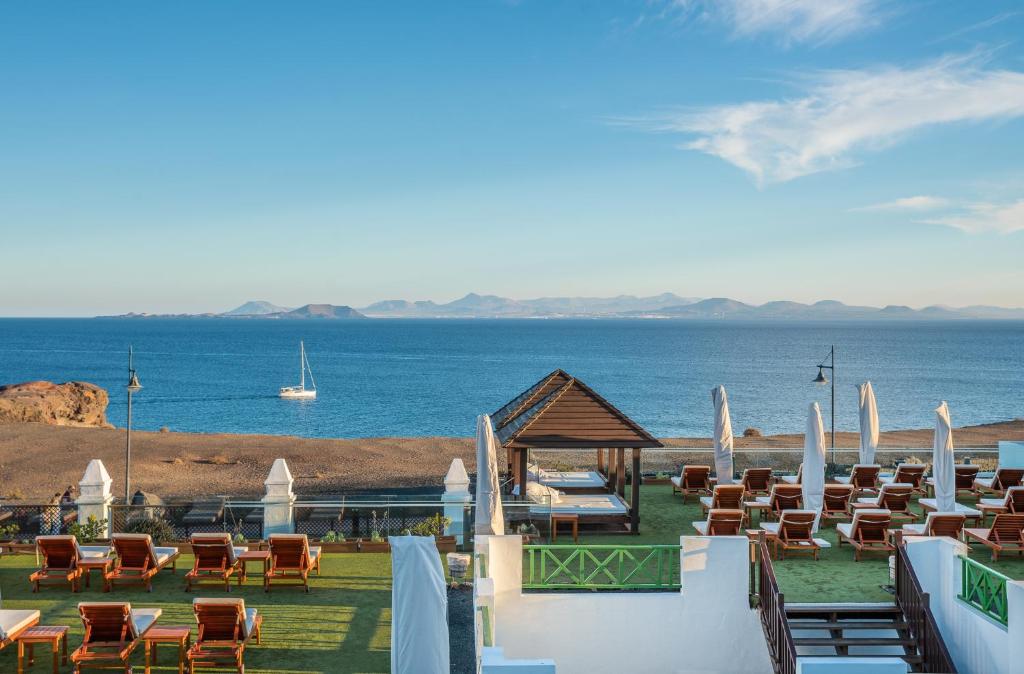 a beach with chairs and a view of the ocean at Hotel LIVVO Volcán Lanzarote in Playa Blanca